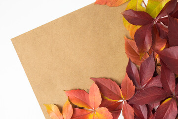 Close up of a vintage brown paper on a white background and autumn fall leaves in the right border.Flat lay, overhead, copy space, top view.