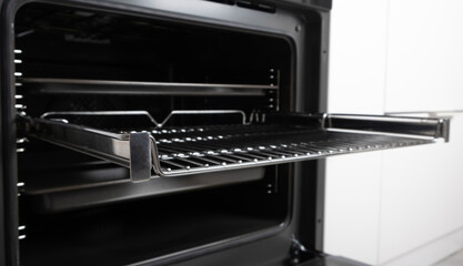 New modern electric oven built in black with screen, convention and grill, empty and open. Telescopic guides. Scandinavian style in a white minimalistic kitchen.