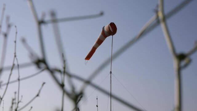 Handheld shot of windsock swaying in the wind at the airport. 
