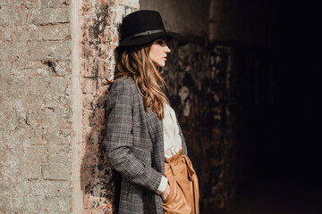  girl in a hat stands by an old brick wall copy space