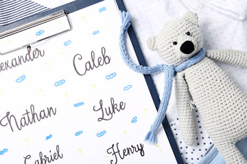 Clipboard with different baby names and toy on child's clothes, closeup