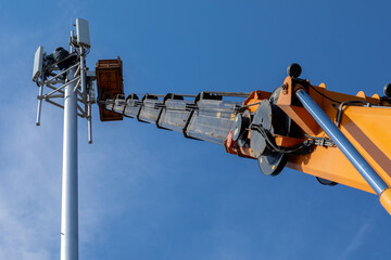Crane with telescopic boom lift used as an aerial working platform. Worker install cellular base...