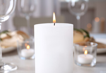 White burning wax candle on table, closeup
