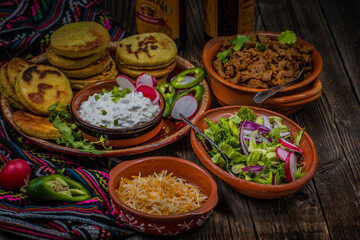 Traditional mexican gorditas with various vegetarian and vegan fillings: seitan, greens, cheese on wooden table