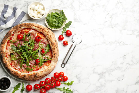 Tasty pizza with meat and arugula on white marble table, flat lay. Space for text