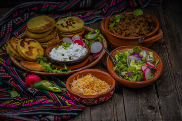 Traditional mexican gorditas with various vegetarian and vegan fillings: seitan, greens, cheese on wooden table