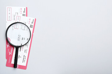 Tickets and magnifying glass on white background, flat lay with space for text. Travel agency concept