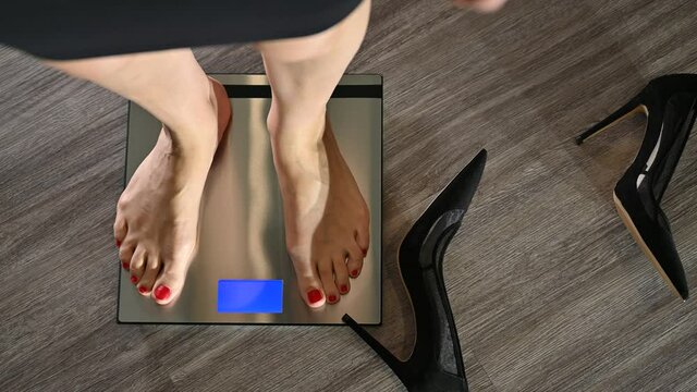 Elegnat women taking her high hill shoes off and stepping on bathroom scale