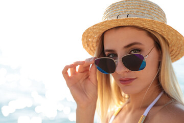 Beautiful woman wearing sunglasses near sea on sunny day