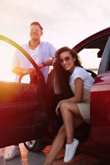 Happy couple near car outdoors at sunset. Summer trip