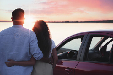 Couple near car outdoors at sunset, back view. Summer trip
