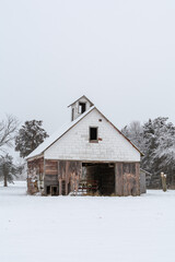 Old rustic wooden barn in the snow on a cold and foggy winter day.  LaSalle county, Illinois.
