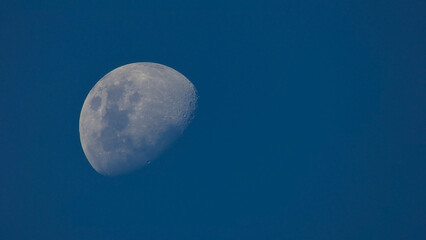 waning moon, seen from the southern hemisphere, moon seen by day with deep blue sky background, photograph of the moon without clouds.