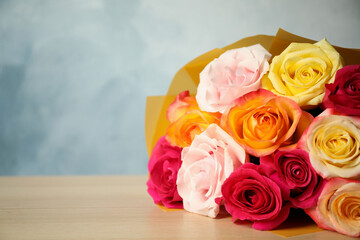 Luxury bouquet of fresh roses on wooden table, closeup. Space for text