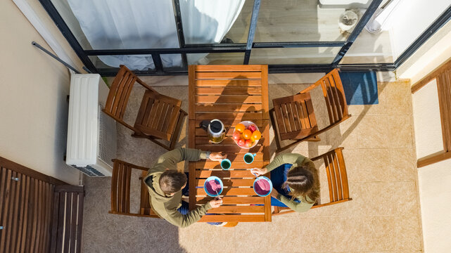 Aerial view of couple having a breakfast on balcony in sunny summer day - Powered by Adobe