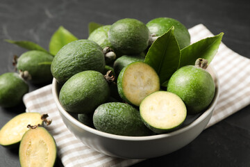 Fresh green feijoa fruits in bowl on black table, closeup