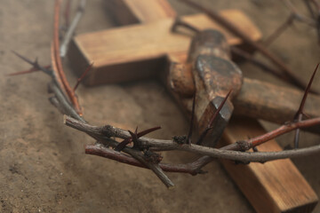Fototapeta na wymiar Crown of thorns, wooden cross and hammer on ground, closeup. Easter attributes