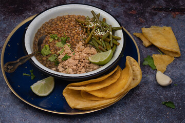 Vegan gluten free bowl consisting of yellow pea stew, scrambled tofu, green beans and corn tortillas on gray table