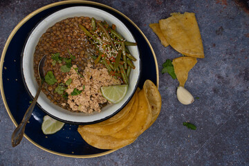 Vegan gluten free bowl consisting of yellow pea stew, scrambled tofu, green beans and corn tortillas on. gray table, copy space