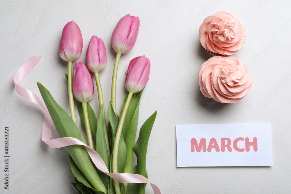 Wall mural 8 March greeting card design with tulips and cupcakes on light grey background, flat lay. International Women's day