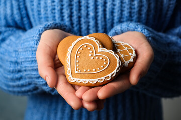 Woman holding tasty heart shaped gingerbread cookies, closeup