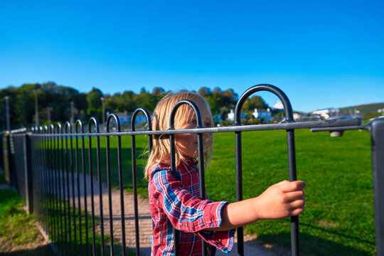Preschooler holding on to gate in park at sunset