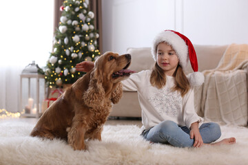 Cute little girl with English Cocker Spaniel in room decorated for Christmas