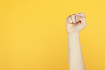 Closeup view of woman showing fist as girl power symbol on yellow background, space for text. 8...