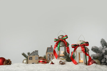 Decorative lanterns and Christmas decor on snow against light grey background