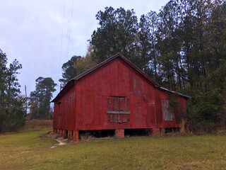 A red barn style building boarded up and abandoned