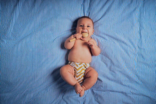 Baby on bed with wooden rattle