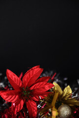 Colorful display of flowers and christmas baubles on black background