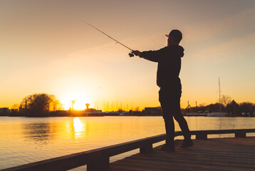 Silhouette of a fisherman casting at sunset