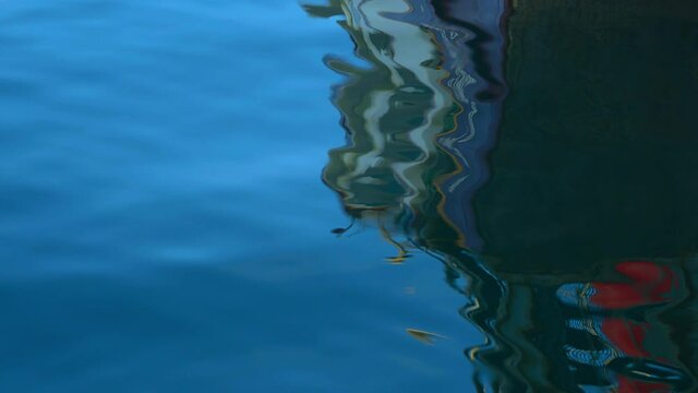 Reflections of a fishing boat in the moving ocean.