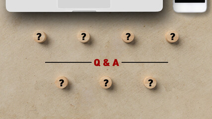 wooden cylinders with questionmarks and with smartphone and notebook and text Q&A on paper background