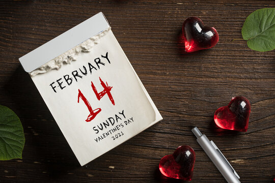 tear-off calendar with Valentine's Day 2021 and heart decoration on top on wooden background