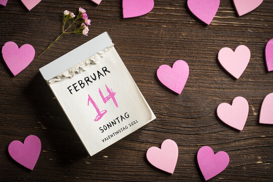 tear-off calendar with Valentine's Day 2021 in German and heart decoration on top on wooden background