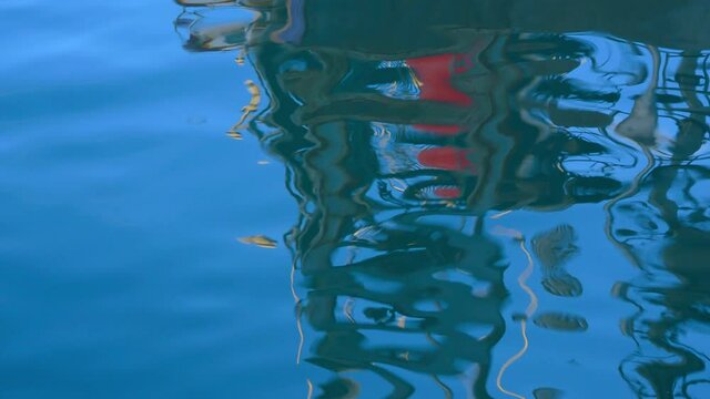 Reflections of a fishing boat in the moving ocean.