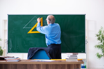 Old male geometry teacher holding triangle