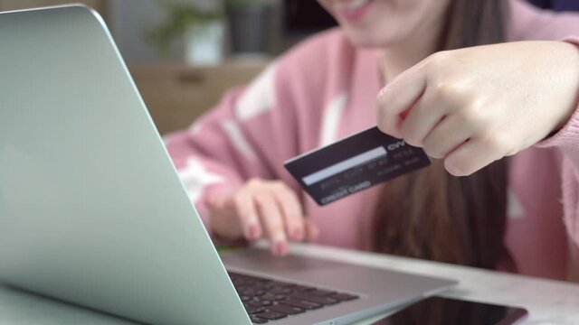 A beautiful woman using computer laptop and credit card to make an online purchasing through E-commerce application during Covid-19 pandemic lockdown. Quarantine, Self Isolation, Payment, New normal.