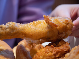手で持っているフライドチキン。