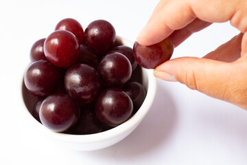 Hand picking grape berries in white bowl