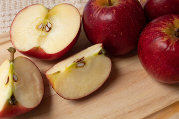 Whole and cut red apples on wooden board