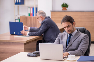 Old boss and young male assistant in the office