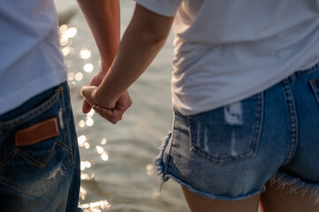 Young couple standing hand in hand on the beach. Couple on a summer vacation at the beach.Summer in love,Valentine day concept.