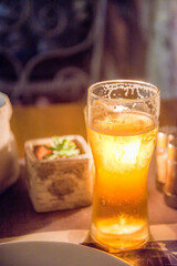 Candlelight shiining through a glass of beer on a restaurant table at night surrounded by condiment bottles ,Kotor,Montenegro.