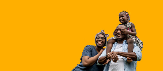 Fototapeta na wymiar Happy African families with a daughter riding their father's neck with yellow backgrounds, color trend 2021.