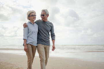 Senior couple embrace walking on the beach, plan life insurance with the concept of happy retirement.