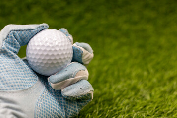 Golfer is holding golf ball on green grass