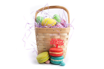 colorful macaroon cookies with a Happy Easter sign and easter eggs in a wooden basket